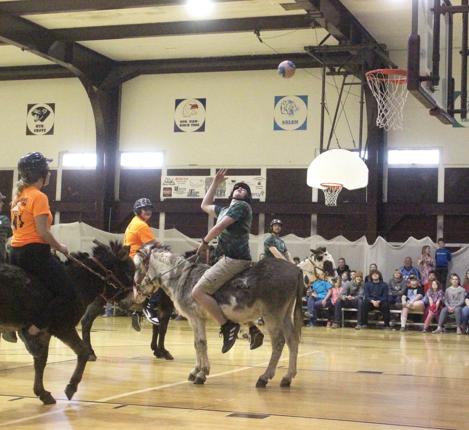 A donkey basketball player launches a hook shot over their shoulder during a contest.